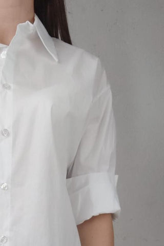 Camicia basica a maniche lunghe con una linea morbida e spalla scesa per un look rilassato. Presenta un classico collo a camicia e una chiusura con bottoni sul davanti.