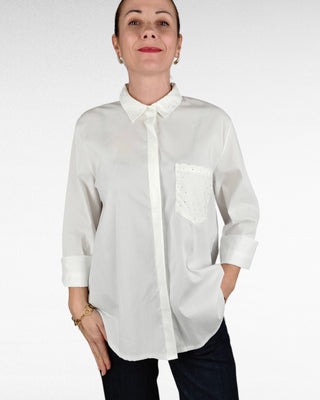 Camicia bianca dal taglio over, più lunga sul retro. Il colletto e il taschino frontale sono impreziositi da luminosi diamantini, regalando un tocco di eleganza e raffinatezza. Ideale da indossare sia per look casual che per occasioni più chic.