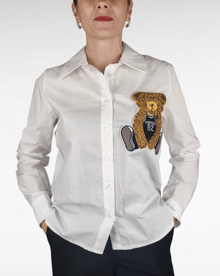 Camicia bianca dal taglio classico, con colletto a punta e chiusura frontale a bottoni. Dettaglio distintivo: un orsetto applicato e cucito sul davanti, che aggiunge un tocco di originalità al capo. Perfetta per chi cerca uno stile raffinato ma con un pizzico di unicità.